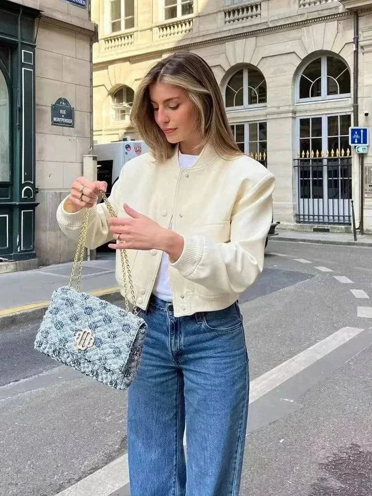 Women's cropped white bomber jacket with long sleeves and button-front closure, styled for autumn and winter fashion.