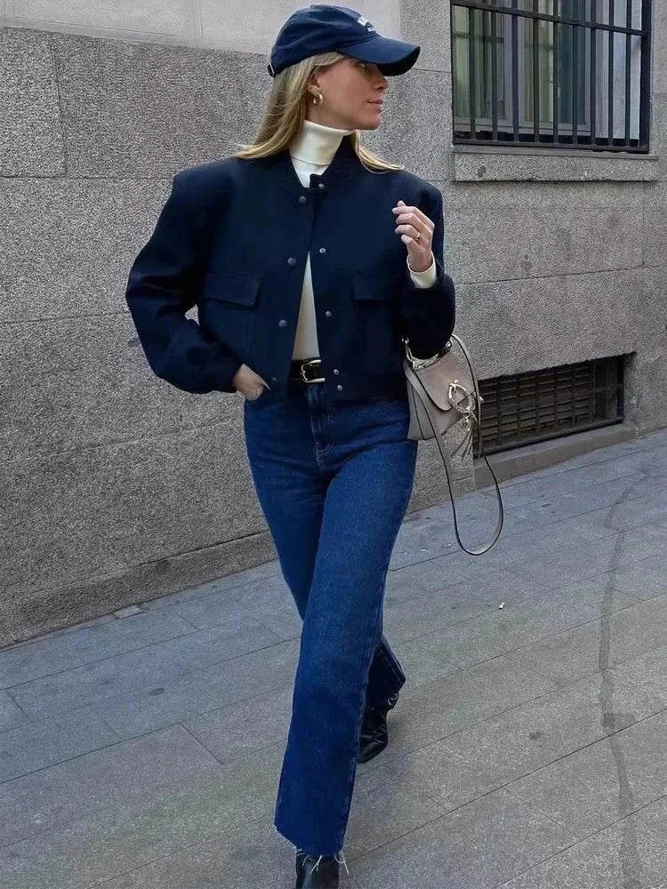 Stylish woman wearing a white cropped bomber jacket and jeans.