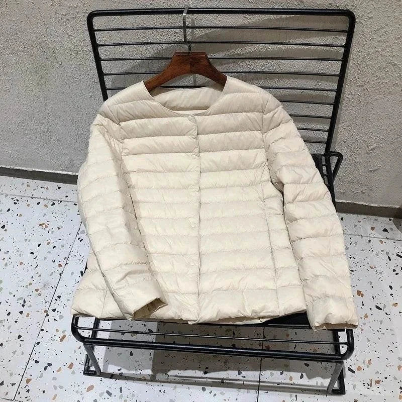 Ultralight warm women's puffer jacket, collarless O-neck design, on a chair.