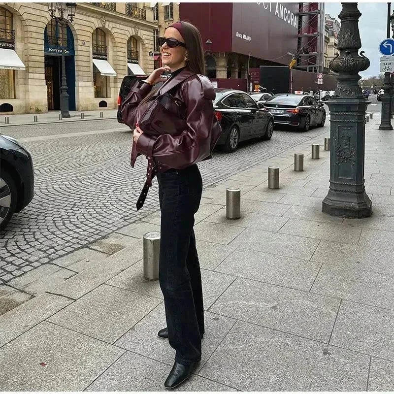 Vintage cropped leather jacket with braid lapel on woman standing in city street.