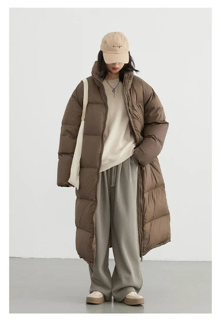 Loose casual women’s long down coat for autumn and winter 2023 with thick insulation and modern design.