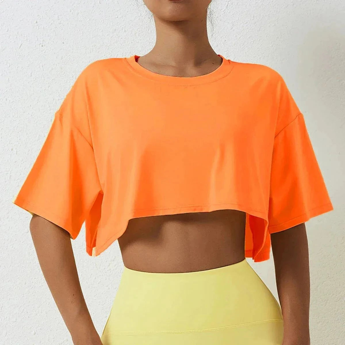 Orange cotton crop top for active women, short sleeve, breathable fabric, navel-baring design, ideal for yoga and workouts.